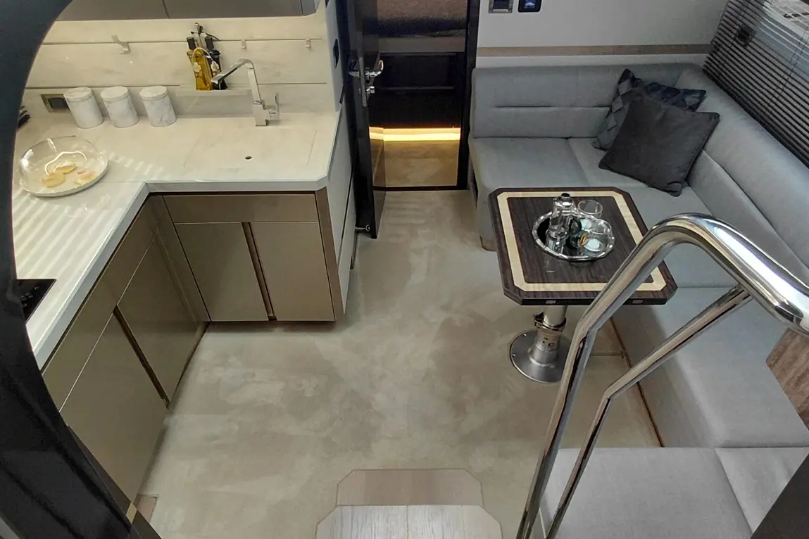 Stylish yacht interior featuring a modern kitchen, seating area, and a table with drinks, showcasing luxury design elements.